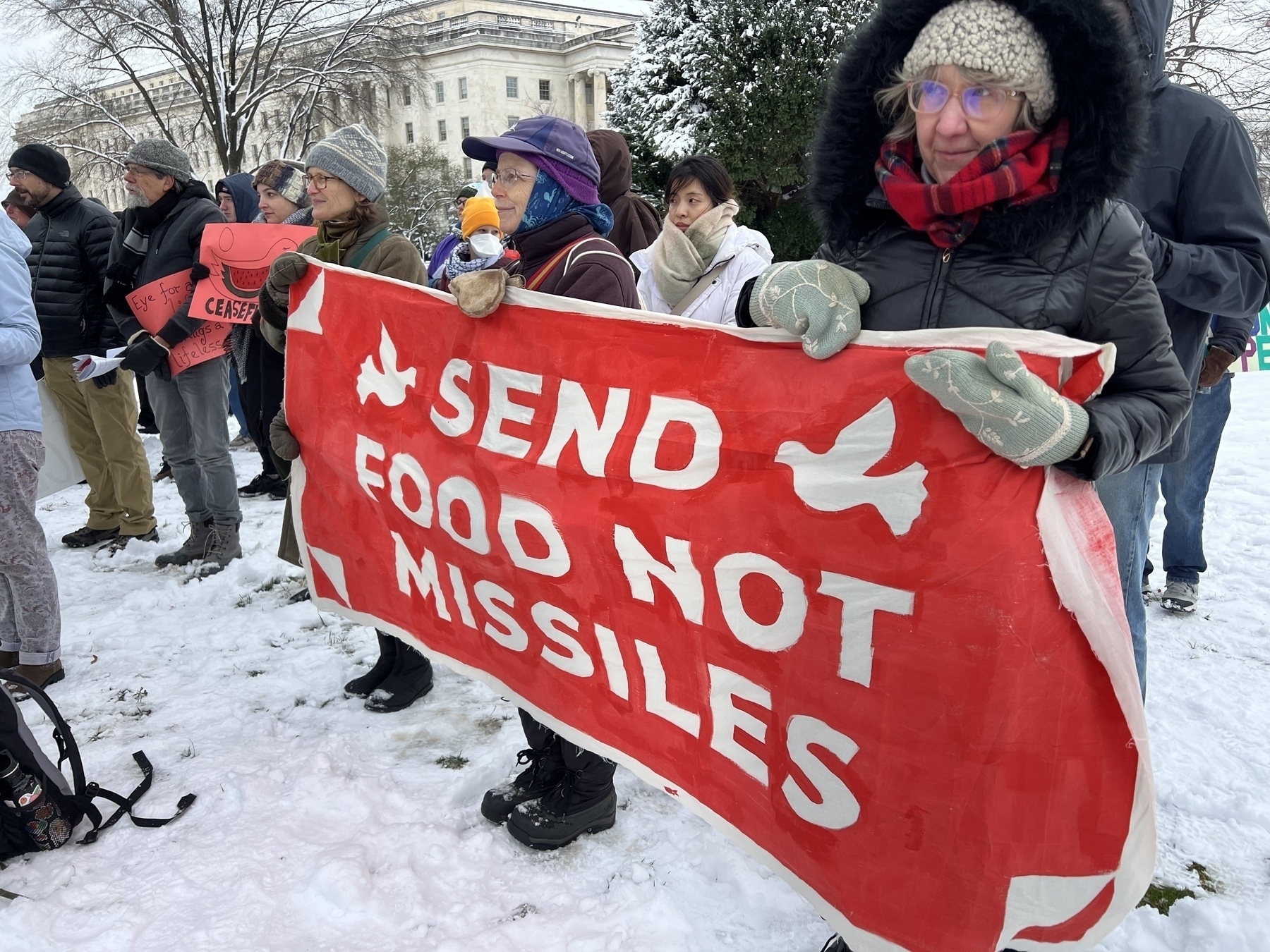 Mennonites outside with a banner that reads “send food not missiles”